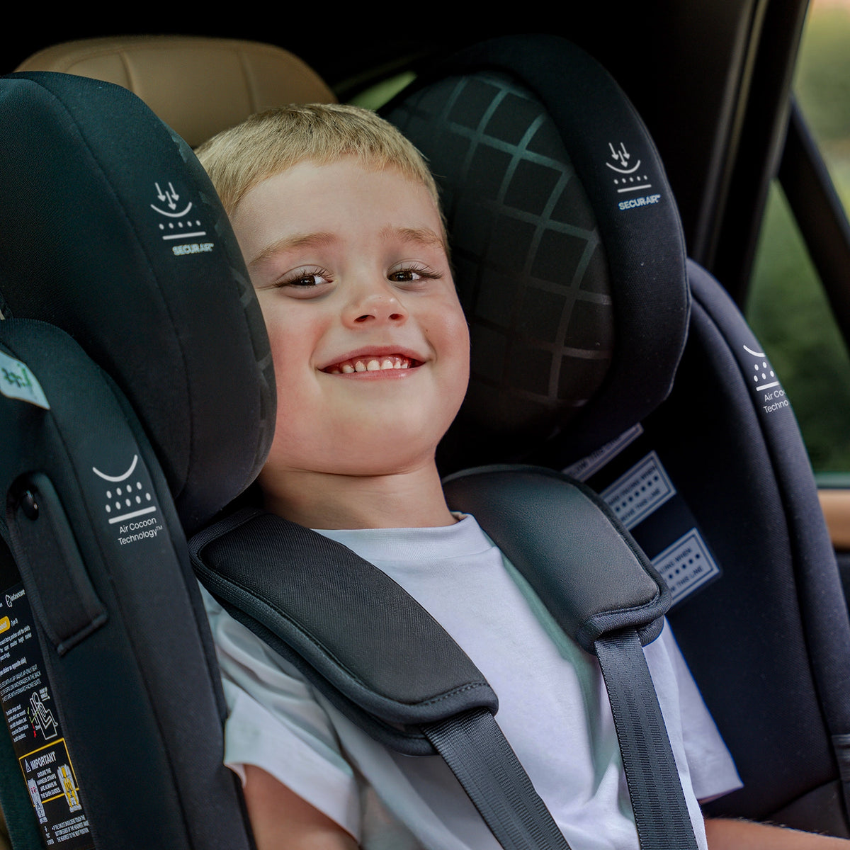 A young boy smiling while seated in the InfaSecure Quattro Onyx car seat inside a vehicle.