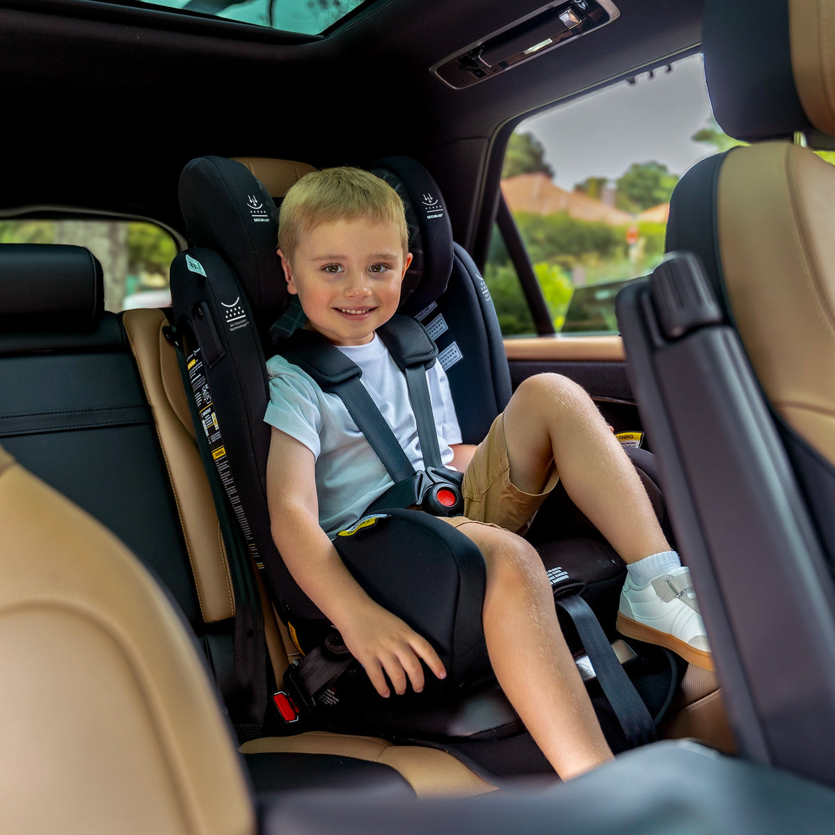 A young boy smiling while seated in the InfaSecure Quattro Onyx car seat inside a vehicle.